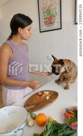 A Woman in a Modern Kitchen is Preparing Healthy and Delicious Snacks for Her Pet Dog A Woman in a Modern Kitchen is Preparing Healthy and Delicious Snacks for Her Pet Dog 130994516