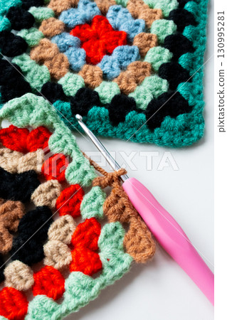 Colorful granny squares with crochet hook on white background Colorful granny squares with crochet hook on white background 130995281