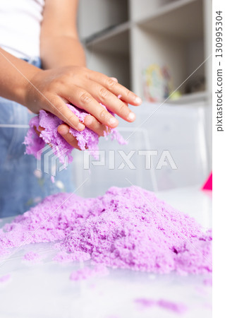Child playing with colorful kinetic sand at home 130995304