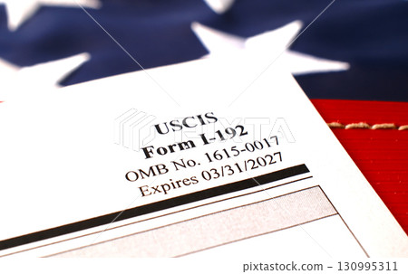 I-192 Application for Advance Permission to Enter as a Nonimmigrant blank form lies on American Flag background 130995311