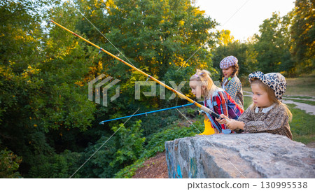 Girls fishing together with colorful rods over stone bridge Girls fishing together with colorful rods over stone bridge 130995538