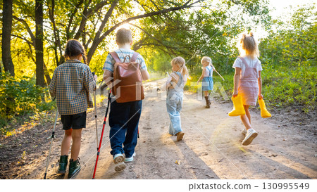 Children walking with yellow boots in hands along forest trail Children walking with yellow boots in hands along forest trail 130995549