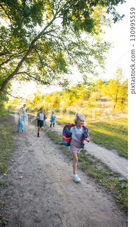Children running joyfully on sunny forest path during outdoor adventure 130995559