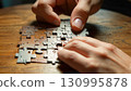 Person Assembling Puzzle on Wooden Table 130995878