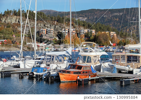 Landscape photo of tranquil marina surrounded by nature, with moored boats 130995884