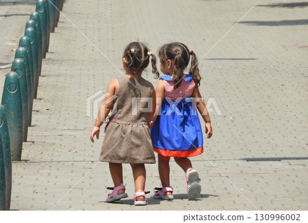 Two young girls walk hand in hand Two young girls walk hand in hand 130996002