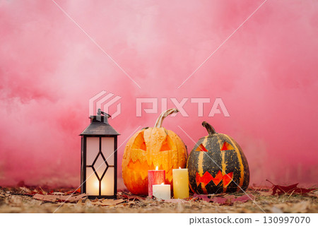 Bright Halloween decorations in front of pink smoke. Halloween concept, pumpkins, lantern, candles 130997070