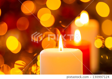 Close-up shot of candle on the background of Christmas tree. Christmas background with copy space 130997124