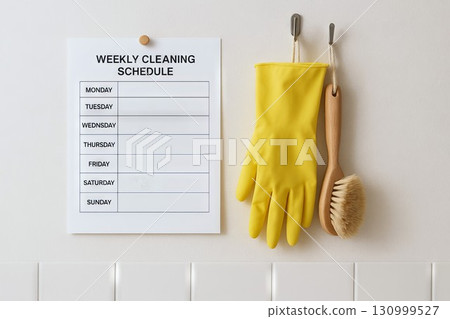 Weekly cleaning schedule on wall with yellow cleaning gloves and brush for simple home organization. concept of household chores, cleaning tools, home maintenance. 130999527