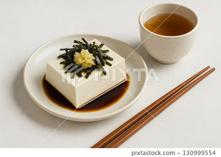 Tofu with ginger and nori served with soy sauce and green tea on minimalist white plate. concept of asian cuisine, healthy eating, elegant meal presentation. Tofu with ginger and nori served with soy sauce and green tea on minimalist white plate. concept of asian cuisine, healthy eating, elegant meal presentation. 130999554