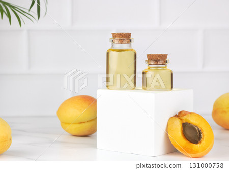 Apricot oil in glass bottles with fresh apricots on white background. Natural skincare, aromatherapy concept. Copy space Apricot oil in glass bottles with fresh apricots on white background. Natural skincare, aromatherapy concept. Copy space 131000758