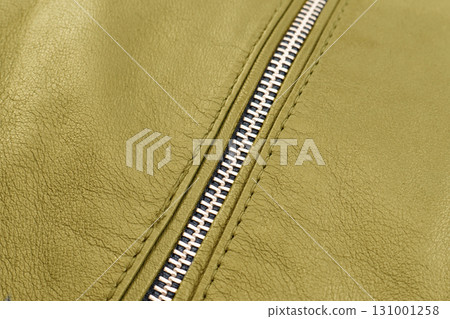 Macro shot of zipper on yellow leather texture background with stitching. Close-up of black leather material Macro shot of zipper on yellow leather texture background with stitching. Close-up of black leather material 131001258
