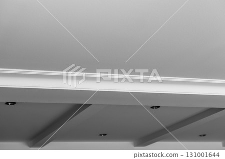 Suspended and grid ceiling with LED spots lamps and drywall construction in empty room in house interior. Stretch ceiling white and complex shape. Suspended and grid ceiling with LED spots lamps and drywall construction in empty room in house interior. Stretch ceiling white and complex shape. 131001644