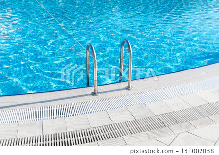 Swimming pool with stair and water. Swimming pool with handrail. Stainless steel ladder in pool. Grab bars ladder in the blue swimming pool 131002038