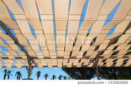 Transparent colored sunshade. Outdoor sunlight diffuser. White fabric awning with the palm tree background. White canvas sun 131002068