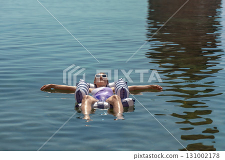 Woman floating water, enjoying summer relaxation on inflatable raft in calm blue lake Woman floating water, enjoying summer relaxation on inflatable raft in calm blue lake 131002178