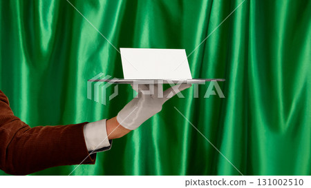 White paper on silver tray held by waiter hand in elegant presentation 131002510