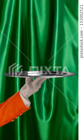 Silver serving tray held by waiter hand with glove on green curtain background Silver serving tray held by waiter hand with glove on green curtain background 131002521