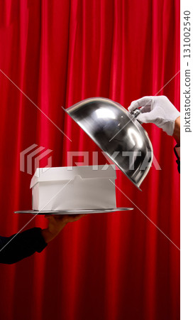 White mockup box presented on silver tray under cloche with red curtain backdrop 131002540