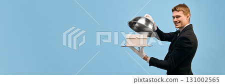 Smiling man in tuxedo holding silver tray with copy space gift box and dome cover Smiling man in tuxedo holding silver tray with copy space gift box and dome cover 131002565