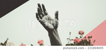A black-and-white hand of a statue extends toward the sky amidst colorful flowers and shapes. A black-and-white hand of a statue extends toward the sky amidst colorful flowers and shapes. 131004045