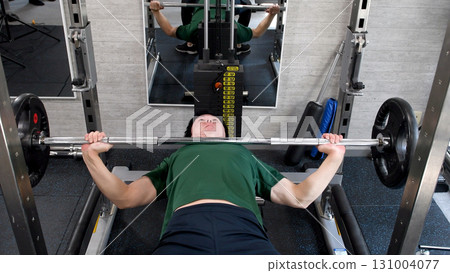 Young man doing bench press in gym 131004077