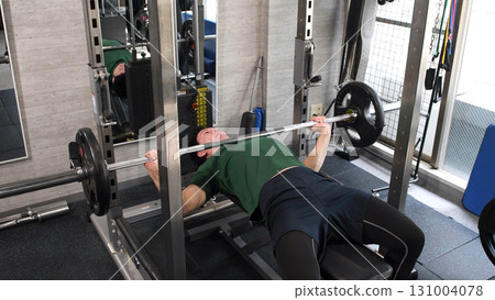 Young man doing bench press in gym 131004078