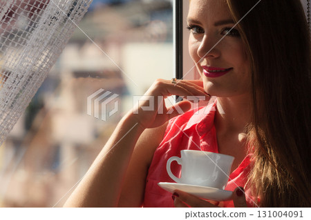 Woman looking through window, relaxing drinking coffee 131004091