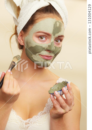 Woman applying with brush clay mud mask to her face Woman applying with brush clay mud mask to her face 131004129