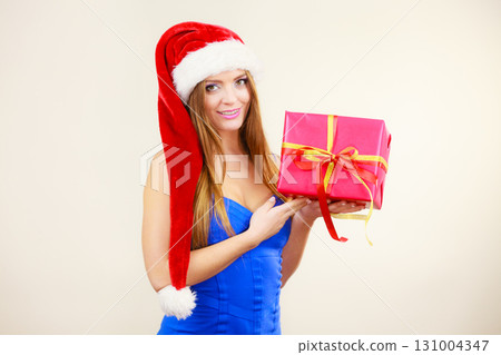 Woman in santa claus hat holds gift box. Christmas time Woman in santa claus hat holds gift box. Christmas time 131004347