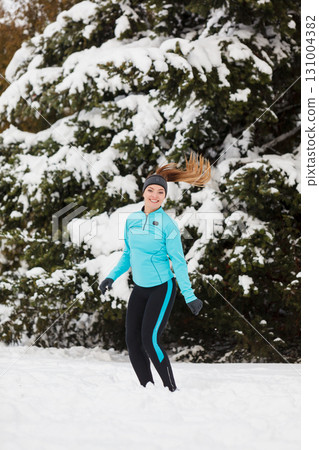 Young girl jumping in the snow. 131004382