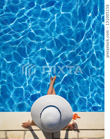 beautiful woman in a hat sitting on the edge of the swimming pool beautiful woman in a hat sitting on the edge of the swimming pool 131005158