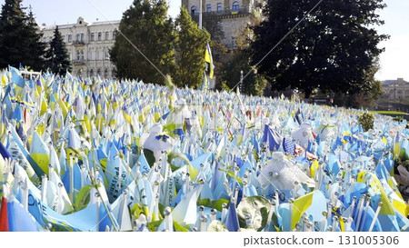 Many small blue-yellow flags with names of the dead war against russia. Memorial of the fallen soldiers, children, women in the capital of Ukraine. Concept of tragedy and misfortune. Close up 131005306