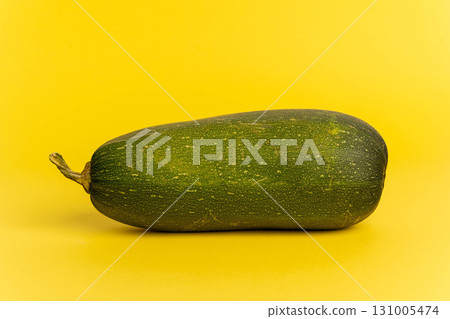 Green zucchini vegetable lying on yellow background Green zucchini vegetable lying on yellow background 131005474