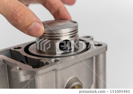 Hand assembling new engine piston into cylinder block Hand assembling new engine piston into cylinder block 131005493