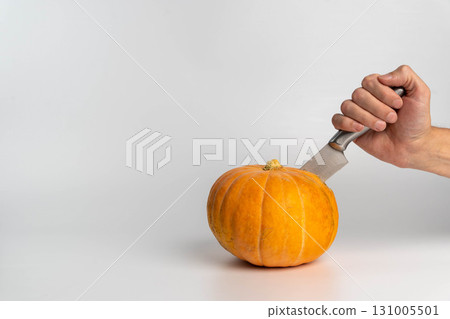 Hand carving pumpkin with knife on white background Hand carving pumpkin with knife on white background 131005501