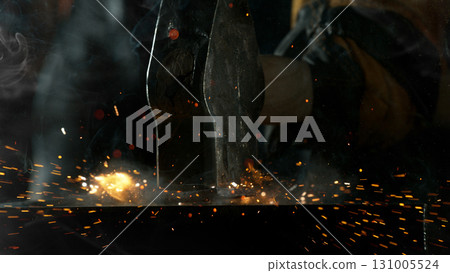 Close-up of blacksmith forging glowing hot iron on anvil with flying sparks Close-up of blacksmith forging glowing hot iron on anvil with flying sparks 131005524