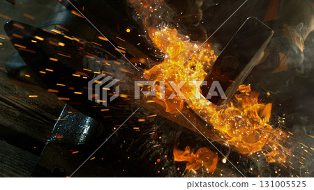 Close-up of blacksmith forging glowing hot iron on anvil with flying sparks 131005525