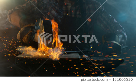 Close-up of blacksmith forging glowing hot iron on anvil with flying sparks 131005530
