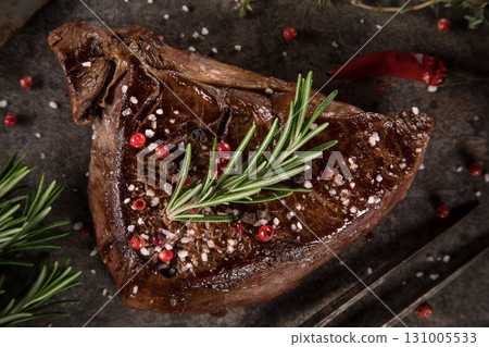 Beef rump steak on black stone table, top down, close-up. 131005533