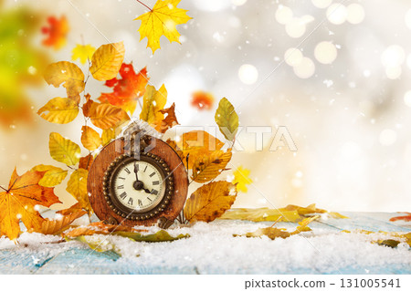 Alarm clock and autumn leaves on table outdoors. Daylight saving time end Alarm clock and autumn leaves on table outdoors. Daylight saving time end 131005541