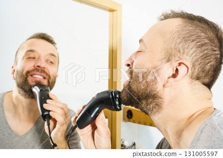 Man shaving trimming his beard Man shaving trimming his beard 131005597