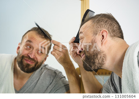 Man using comb in bathroom 131005604