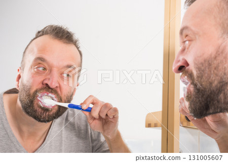 Man brushing his teeth in bathroom Man brushing his teeth in bathroom 131005607