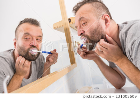 Man brushing his teeth in bathroom Man brushing his teeth in bathroom 131005609
