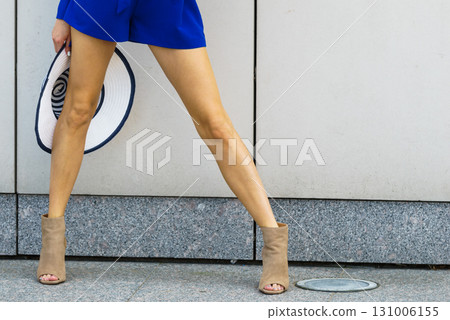 Woman wearing blue dress holding sun hat Woman wearing blue dress holding sun hat 131006155