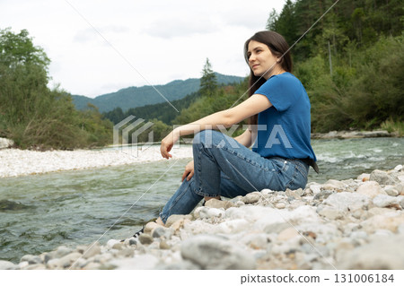 Young beautiful woman sitting on the bank of the river. Young beautiful woman sitting on the bank of the river. 131006184