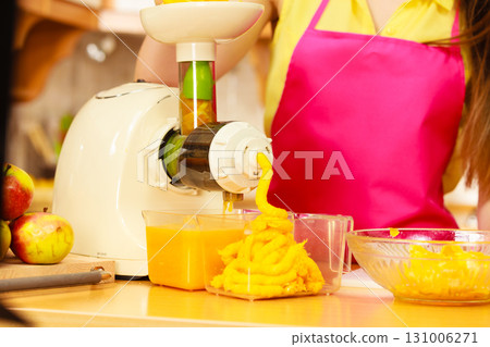 Woman making orange juice in juicer machine Woman making orange juice in juicer machine 131006271