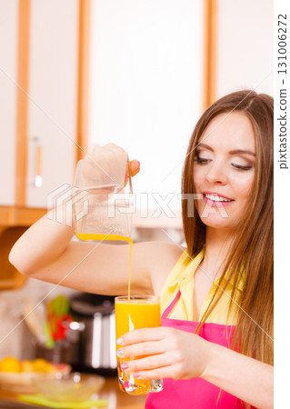Woman make orange juice in juicer machine pouring drink in glass 131006272