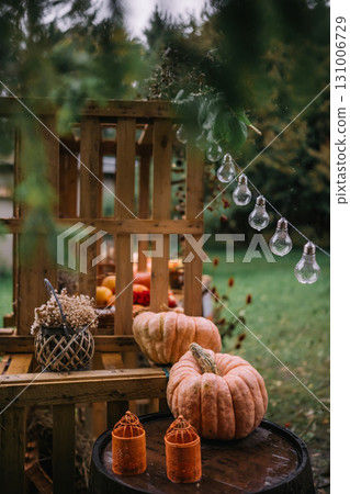 Decorative autumn display featuring pumpkins and string lights in a cozy outdoor setup 131006729